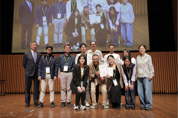 Group holding certificates posing together on stage