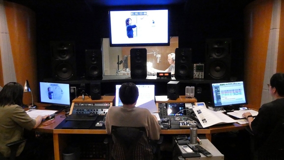 Chris Wells recording in the booth as 3 staff watch outside