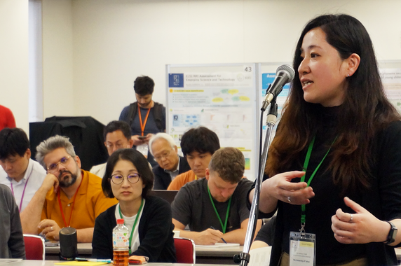 質問者の女性がマイクを持ち、参加者に向けて発言している様子