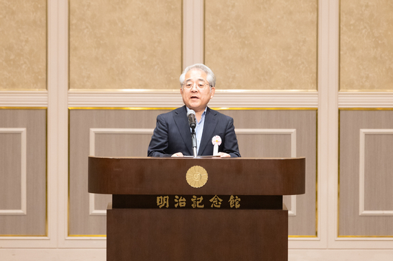 演台のマイクに向かって参加者に挨拶をする杉野理事長