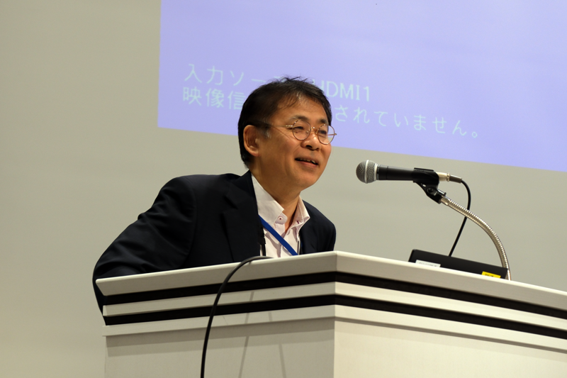 Mr. KIYOURA speaking into a microphone.